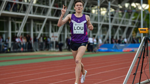 Runner in purple on track with 'LOU' bib, gesturing mid-stride.